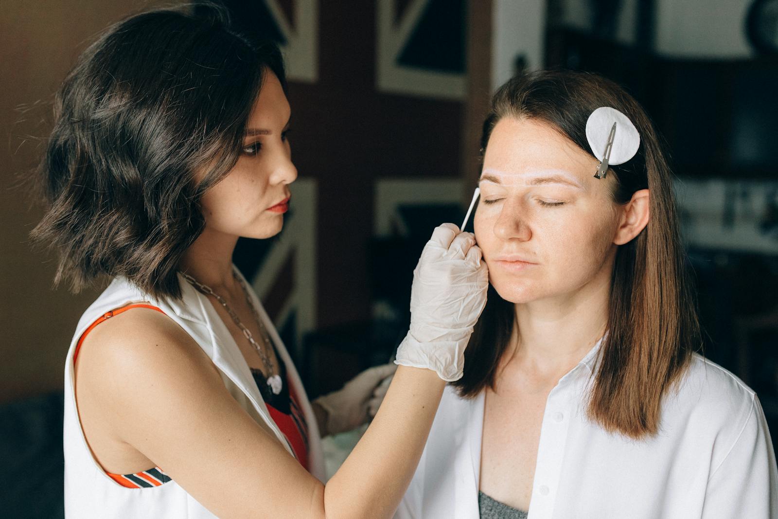 A skilled makeup artist applies makeup to a client in a professional indoor setting.